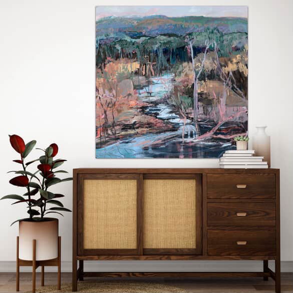 Wooden sideboard with a painting of a landscape above it, featuring a plant to the left.